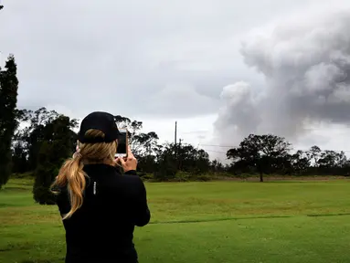 Marie Brant, dari California, mengambil gambar asap tebal yang berembus dari puncak gunung berapi Kilauea di Hawaii. Kamis (17/5). Para wisatawan tetap santai dan justru menjadikan letusan gunung ini sebagai objek wisata. (AP Photo/Caleb Jones)
