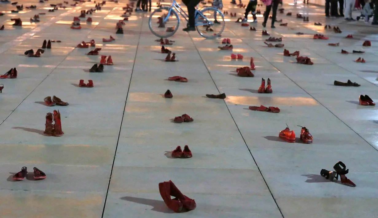 Orang-orang berjalan melewati instalasi ratusan sepatu merah untuk memprotes kekerasan terhadap perempuan di kota pesisir Tel Aviv, Selasa (4/12). Sepanjang tahun ini, 24 perempuan Israel tewas akibat tindakan kekerasan dalam rumah tangga. (JACK GUEZ/AFP)