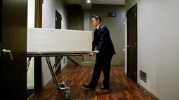 Petugas memindahkan peti jenazah ke sebuah kamar di 'Corpse Hotel', Kawasaki, Jepang, 20 April 2016. Dengan tarif setara Rp 1,1 juta, konsumen dapat menyimpan jenazah kerabatnya untuk periode 4 hari, sebelum dikirim ke krematorium. (REUTERS/Thomas Peter)