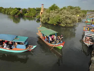Perahu wisata melintasi kerumunan wisatawan yang berjalan di atas Jembatan Cinta di Wisata Mangrove, Tarumajaya, Bekasi, Minggu (30/12). Wisata tersebut berbatasan langsung dengan kawasan Marunda Jakarta Utara. (merdeka.com/Arie Basuki)