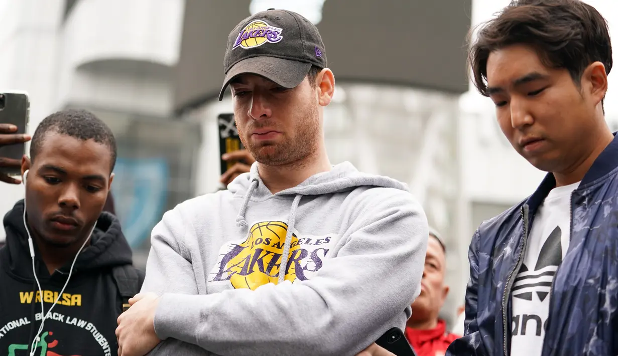 Fans LA Lakers tampak sedih usai Kobe Bryant meninggal dunia di Staples Center, Minggu (26/1/2020). Legenda basket NBA itu wafat dalam kecelakaan helikopter di Calabasas, California. (AFP/Rachel Luna)