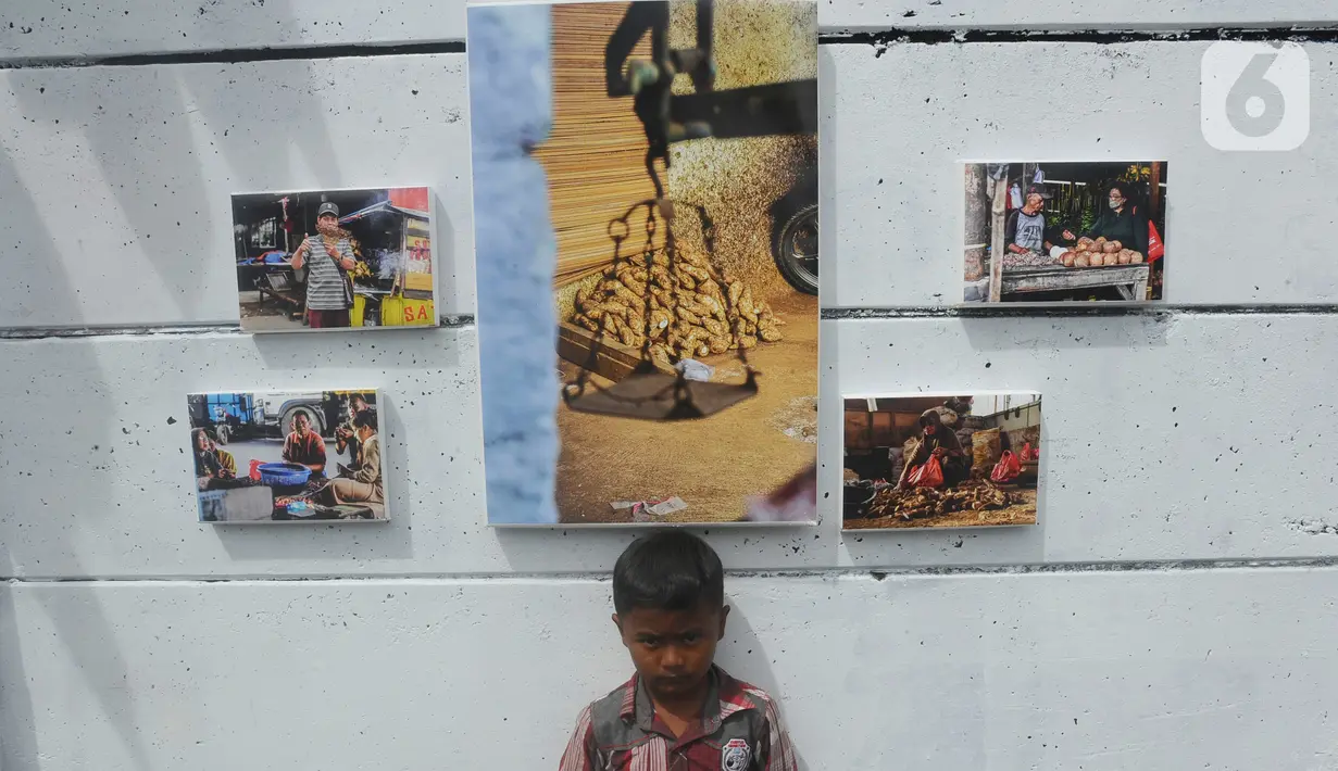 Seorang anak berpose di dekat karya foto selama kegiatan pameran Lensa Anak Terminal di Sekolah Master, Depok, Jawa Barat, Rabu  (8/2/2023). Pameran 170 karya foto dari 12 anak-anak terminal di kawasan tersebut merupakan hasil pembelajaran bersama Komunitas Lensa Anak Terminal dan berlangsung  hingga 12 Februari 2023. (merdeka.com/Arie Basuki)