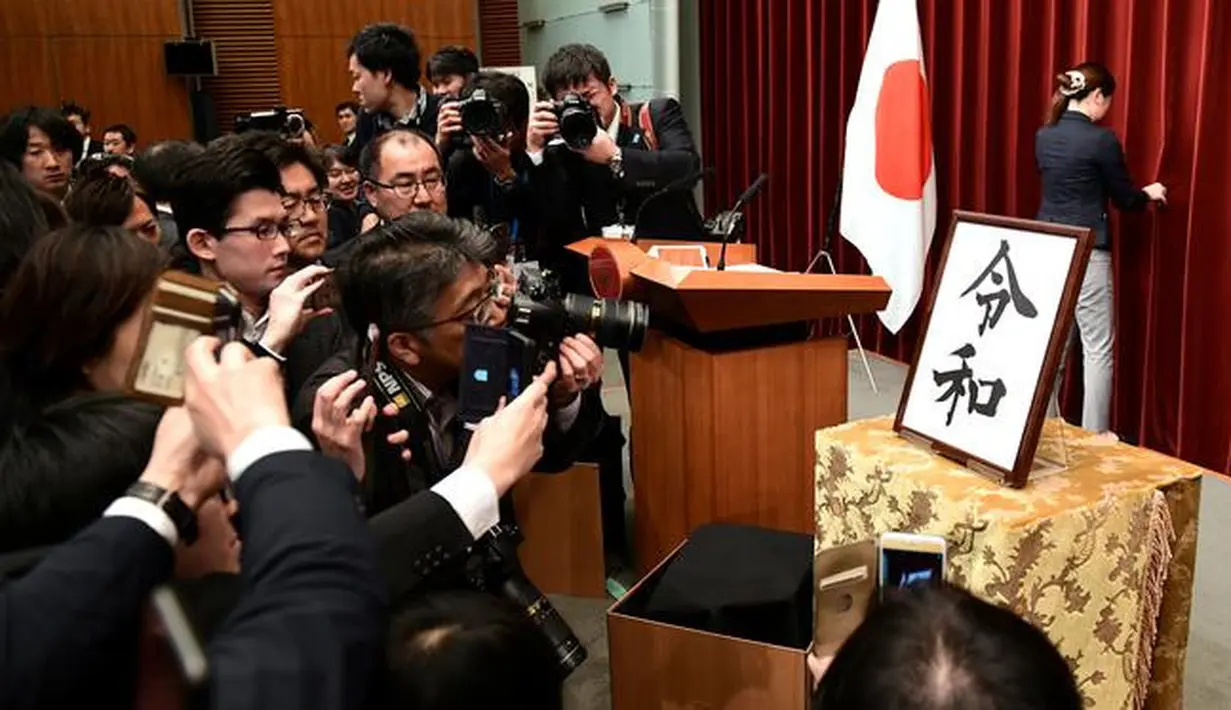 Awak media mengambil gambar plakat nama era baru Kekaisaran Jepang, yakni Reiwa, setelah konferensi pers di kantor perdana menteri, Tokyo, Senin (1/4). Reiwa, menjadi nama era yang baru Jepang mulai 1 Mei 2019 setelah Kaisar Akihito turun takhta pada akhir April mendatang. (Kazuhiro NOGI / AFP)