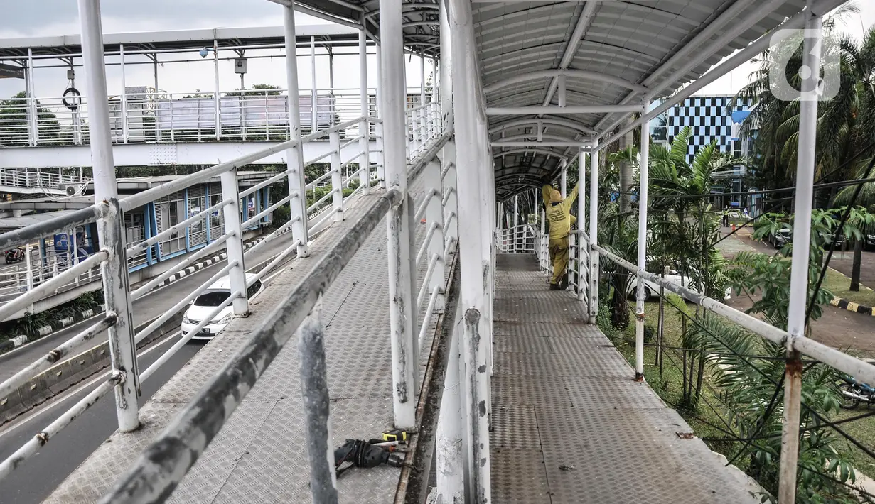 Petugas Sudin Bina Marga Jakarta Timur memperbaiki jembatan penyeberangan orang (JPO) di Jalan Otto Iskandardinata (Otista), Jatinegara, Rabu (9/2/2022). Perbaikan JPO itu tindak lanjut pasca insiden tertimpa pohon tumbang pada November tahun lalu akibat cuaca ekstrem. (merdeka.com/Iqbal S Nugroho)