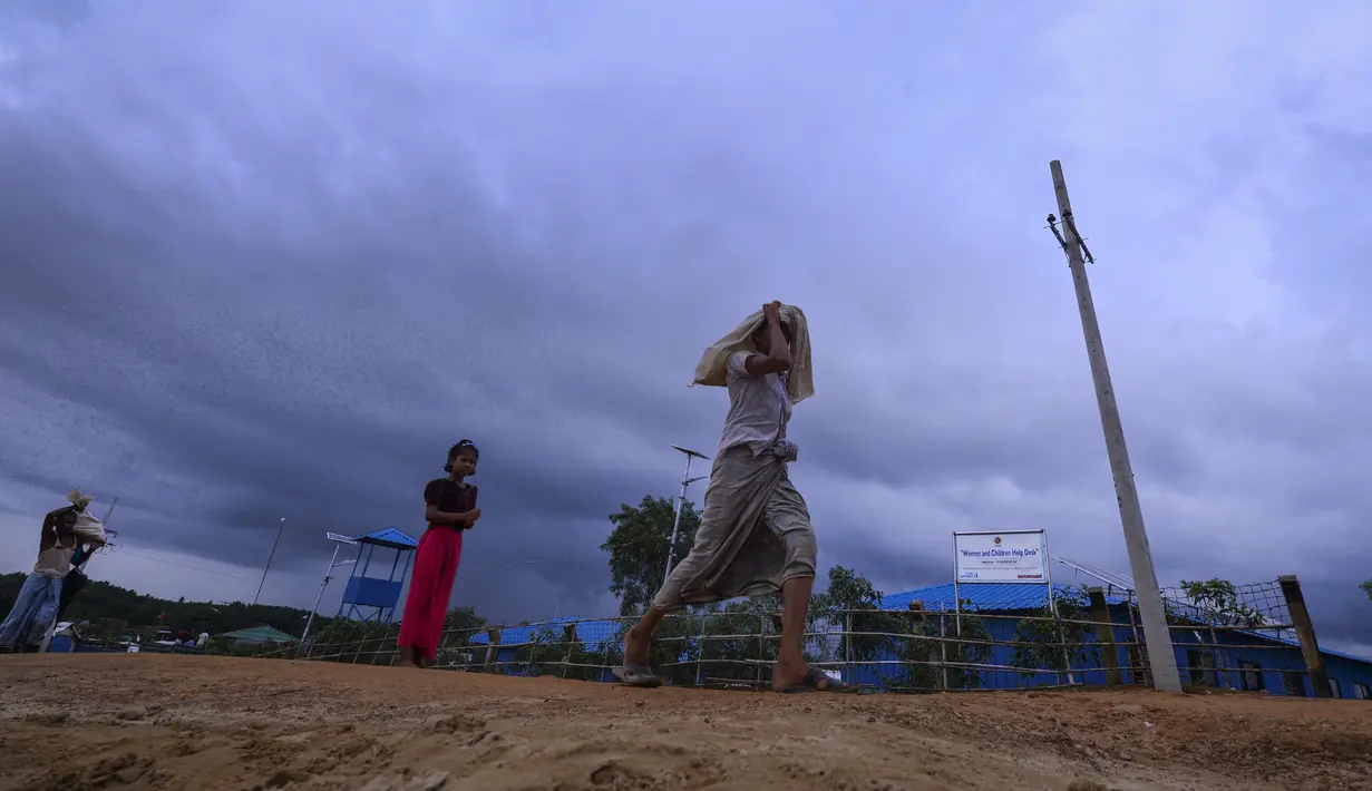 Seorang anak Rohingya berjalan menuju rumahnya di Kamp Pengungsi Kutupalong di Cox's Bazar, Bangladesh, Senin (22/7/2019). Lebih dari satu juta etnis Rohingya melarikan diri dari Myanmar dan menetap di Kutupalong yang merupakan salah satu kamp pengungsi terbesar di dunia. (MUNIR UZ ZAMAN/AFP)
