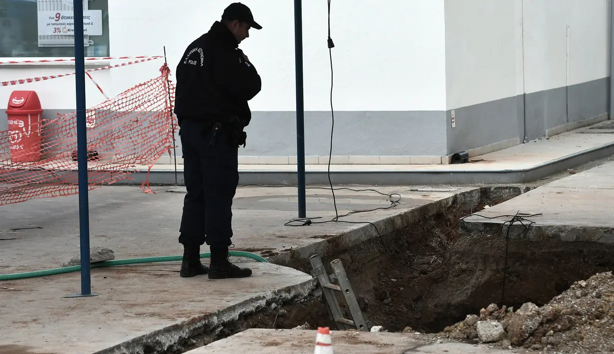 Seorang polisi mengamati sebuah lubang ditemukannya bom dari masa Perang Dunia II di Kota Thessaloniki, Yunani, 9 Februari 2017. Penemuan bom yang mengandung sekitar 250 kg bahan peledak itu memicu evakuasi sekitar 60 ribu warga. (SAKIS MITROLIDIS/AFP)