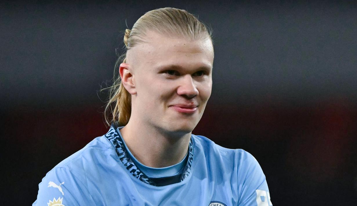 Pemain Manchester City memamerkan badge trofi Premier League kehadapan fans Arsenal. Hal itu dilakukan bomber asal Norwegia untuk membalas ejekan fans The Gunners. (AFP/Glyn Kirk)