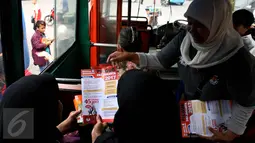 Petugas KPU membagikan brosur kepada penumpang bus saat sosialisasi Pilkada DKI 2017 di Terminal Senen, Jakarta, Minggu (18/12). Sosialisasi pesta demokrasi ini guna mencegah banyaknya pemilih yang golongan putih atau golput. (Liputan6.com/Johan Tallo)