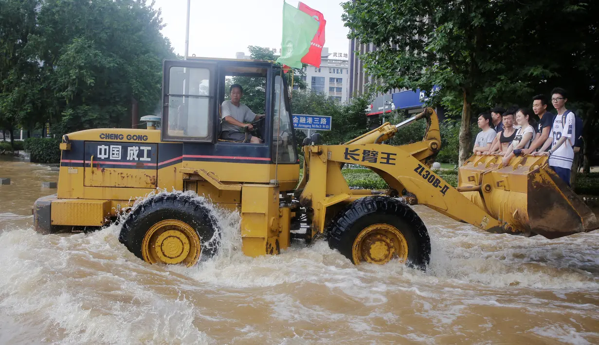 Pekerja mengendarai ekskavator saat membawa para warga menuju kantor di Wuhan, provinsi Hubei, (8/7). Banjir hebat yang belum juga surut membuat warga kesulitan menjalani aktivitasnya. (REUTERS/Stringer)