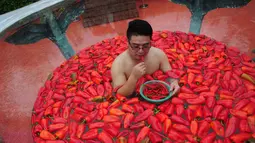Peserta memakan cabai selama kompetisi makan cabai di Ningxiang, Provinsi Hunan, Tiongkok, 12 Agustus 2017. Peserta tak hanya diwajibkan memakan cabai, mereka peserta juga akan direndam dalam gentong berisi cabai yang direndam air. (STR / AFP)
