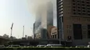 Jalanan di sekitar lokasi kebakaran ditutup, seiring membumbungnya asap hitam tebal dari lokasi kejadian, Uni Emirat Arab, Minggu (2/4).  Belum ada laporan jatuhnya korban tewas atau luka dari peristiwa kebakaran tersebut. (AP Photo/ Maggie Hyde)