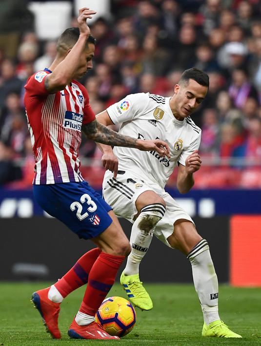 Gelandang Real Madrid,  Lucas Vazquez berebut bola dengan striker Atletico Madrid, Vitolo selama pertandingan lanjutan La Liga Spanyol di stadion Wanda Metropolitano (9/2). Real Madrid menang 3-1 atas Atletico. (AFP Photo/Pierre-Philippe Marcou)