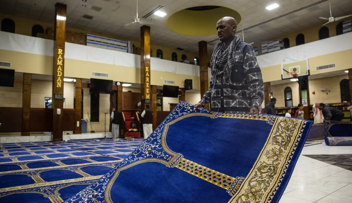 Seorang pria muslim menghamparkan karpet saat akan salat tarawih di Dar Al Hijrah Islamic Center, Falls Church, Virginia, Amerika Serikat, 11 Mei 2019. Populasi muslim di AS telah meningkat dalam seratus tahun terakhir, sebagain besar didorong oleh adanya imigran. (REUTERS/Amr Alfiky)