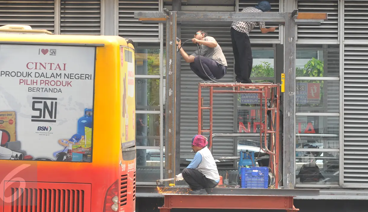 Pekerja merenovasi halte Busway Harmoni, Jakarta, Jum'at (29/1/2016). Perbaikan dilakukan pada jalur masuk penumpang karena sempat ambruk beberapa waktu lalu. (Liputan6.com/Faisal R Syam)