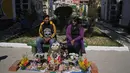 Sepasang suami istri duduk dengan tengkorak manusia yang dihias untuk diberkati oleh seorang imam di Pemakaman Umum selama Festival Natitas di La Paz, Bolivia, Selasa (8/11/2022). Tradisi tahunan ini merayakan kematian di Bolivia dengan tengkorak yang dirawat dan didekorasi oleh mereka yang menggunakannya sebagai jimat untuk perlindungan. (AP Photo/Juan Karita)