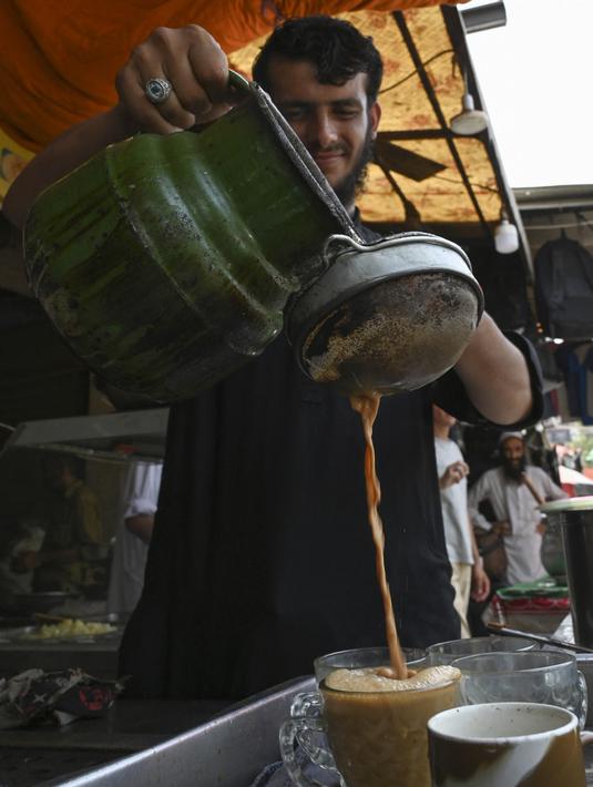 Seorang pekerja menuangkan cangkir teh untuk pelanggan di sebuah restoran di Islamabad, Pakistan, Rabu (15/6/2022). Pakistan tengah berusaha mengurangi tagihan impornya untuk menghemat devisa di tengah pelemahan rupee terhadap dolar AS. (Aamir QURESHI / AFP)