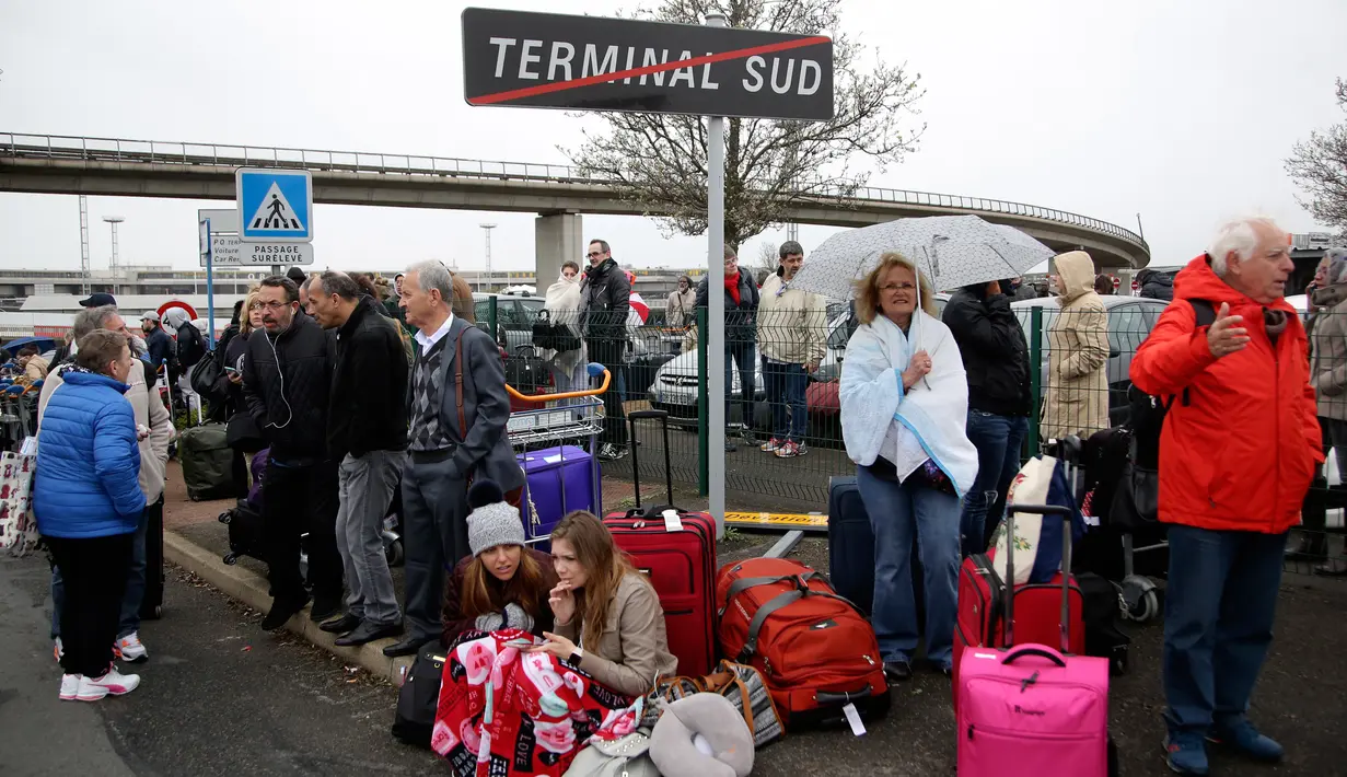 Pengunjung bandara berkumpul di sebuah titik saat usai dievakuasi petugas, Bandara Orly, Prancis, Sabtu (18/3). Evakuasi dilakukan karena terjadi insiden penembakan di Terminal Selatan sekitar pukul 08.30 waktu setempat. (AP Photo)