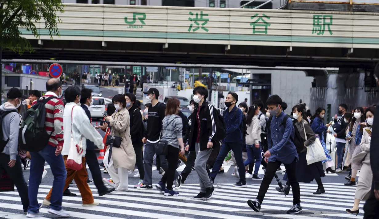 Orang-orang mengenakan masker berjalan melintasi penyeberangan pejalan kaki pada awal liburan "Minggu Emas" Jepang di distrik Shibuya, Tokyo, Kamis (29/4/2021). Golden Week atau Minggu Emas adalah periode di akhir bulan April sampai minggu pertama bulan Mei. (AP Photo/Eugene Hoshiko)