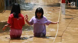 Dua anak melintasi banjir yang menggenangi kawasan Pejaten Timur, Jakarta, Jumat (26/4). Banjir yang berasal dari luapan Sungai Ciliwung tersebut merendam ratusan rumah warga hingga kedalaman lebih dari satu meter. (Liputan6.com/Immanuel Antonius)