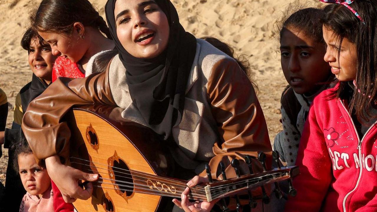 Musisi cantik Pelestina, Ruaa Hassouna memainkan musik untuk anak-anak di Rafah, Jalur Gaza bagian selatan, pada 18 Desember 2023. Aksi ini dilakukan untuk menghibur dan mendukung kesehatan mental anak-anak Jalur Gaza dari trauma kengerian perang.