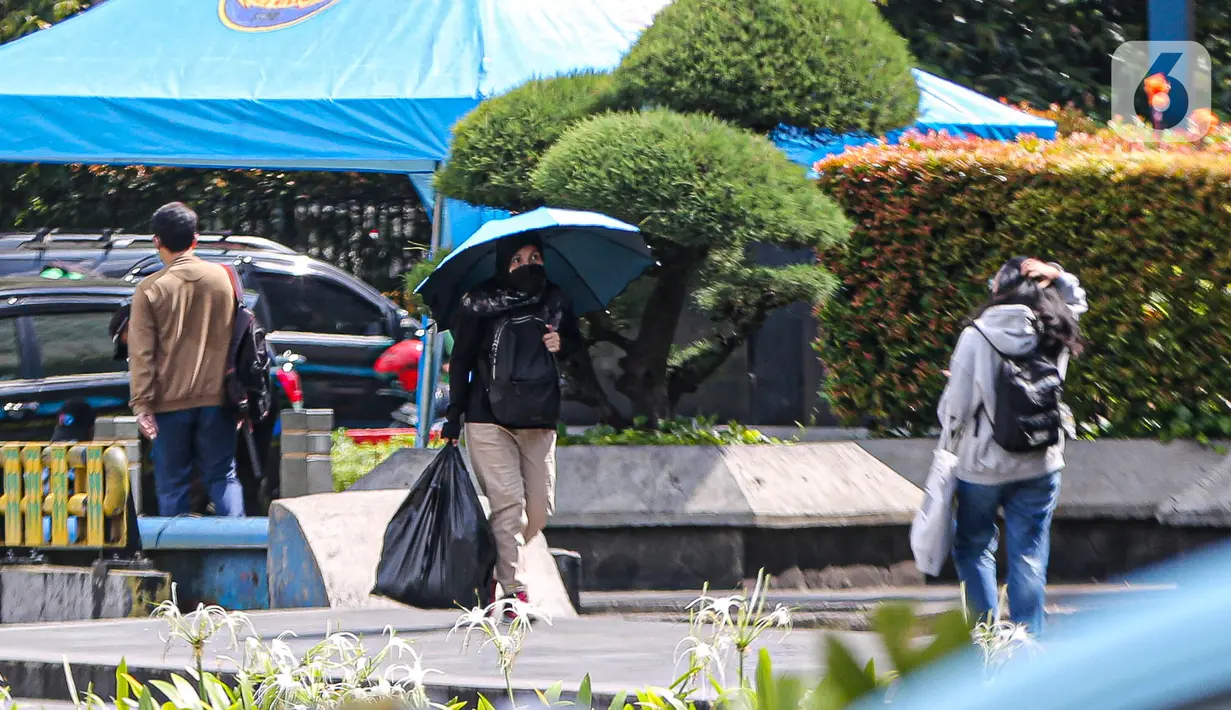 Warga menggunakan payung untuk menghidari paparan sinar matahari saat jalan di kawasan Bundara Hi, Jakarta, Jumat (14/4/2023). (Liputan6.com/Faizal  Fanani)