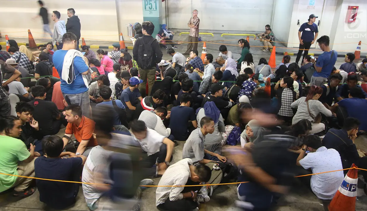 Pengunjung duduk di lantai area parkir saat mengantre masuk ke dalam Nike Bazaar di Mal Grand Indonesia, Jakarta, Rabu (23/8). Mereka mengantre demi mendapat stempel agar bisa mengakses diskon sepatu hingga 90 persen. (Liputan6.com/Immanuel Antonius)