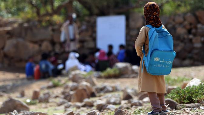 Seorang anak melihat teman-temanya mengikuti kelas terbuka di desa al-Kashar Yaman barat daya, provinsi Taez (16/9/2019). Dua pertiga sekolah rusak dalam serangan, 27 persen ditutup dan tujuh persen digunakan militer atau sebagai tempat perlindungan bagi para pengungsi. (AFP Photo/Ahmad Al-Basha)