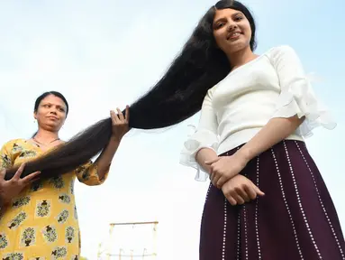 Gadis asal India, Nilanshi Patel (17) berpose dengan ibunya, Kaminibenat di kota Modasa, sekitar 110 Km dari Ahmedabad, Minggu (19/1/2020). Patel mendapat penghargaan Guinness World Record sebagai remaja yang punya rambut terpanjang di dunia dengan panjang hingga 190 cm. (SAM PANTHAKY/AFP)