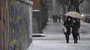 Dua wanita berjalan saat salju turun di Madrid, Spanyol, Jumat (8/1/2021). Badai Filomena mengakibatkan salju lebat turun di Madrid dan seluruh Spanyol. (PIERRE-PHILIPPE MARCOU/AFP)