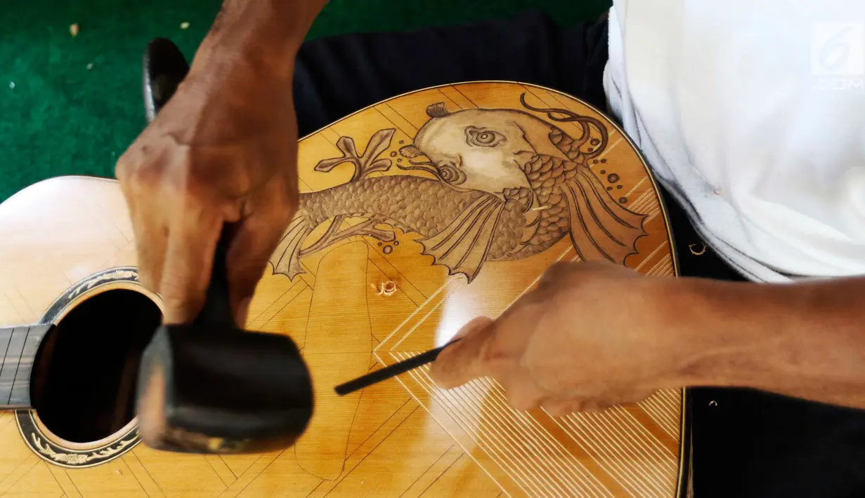 Pekerja tengah mengukir gitar di workshop I Wayan Tuges  gitar berlabel Blueberry di Jalan Baruna No. 5 Guwang, Sukowati, Bali, Senin (15/10). Gitar-gitar produksinya itu dibanderol seharga puluhan juta rupiah. (Liputan6.com/Angga Yuniar)