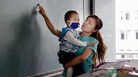 Zhang Wei, seorang guru di China terpaksa mengajar sambil menggendong anaknya yang lemah karena penyakit leukimia yang dideritanya. 
