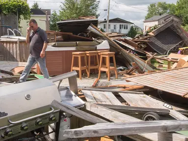 Seorang pria melewati puing-puing rumahnya akibat tornado di Lachute, Barat laut Montreal, Quebec, Rabu (23/8). Badai tornado EF-1 mencapai sekitar 175 km/jam melanda kota-kota di Kanada. (Ryan Remiorz/The Canadian Press via AP)