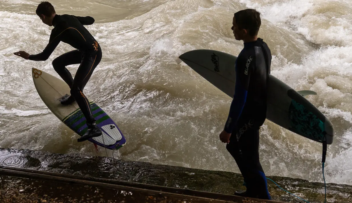 Peselancar meniti ombak saat bermain "surfing" di sungai buatan Eisbach yang terletak di English Garden Munich, Jerman pada 28 Mei 2019. Aliran air sungai Sungai Eisbach yang memiliki lebar 12 meter ini berasal dari Sungai Isar. (Photo by Peter Kneffel/dpa/AFP)