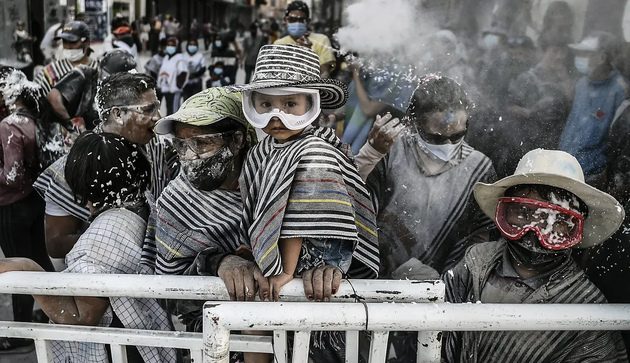Orang-orang bermain dengan bedak dan busa di jalan selama Karnaval Hitam Putih di Pasto, Kolombia (6/1/2022). Karnaval Hitam Putih dirayakan setiap tahun dan telah masuk dalam daftar warisan budaya takbenda UNESCO sejak 2009. (AFP/Joaqin Sarmiento)