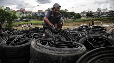 Pekerja mengumpulkan ban mobil bekas di kawasan Petamburan, Jakarta, Minggu (12/12/2021). Keterbatasan lahan membuat para pengepul terpaksa mengumpulkan limbah ban bekas dari seluruh kawasan bantaran Kanal Banjir Barat. (Liputan6.com/Faizal Fanani)