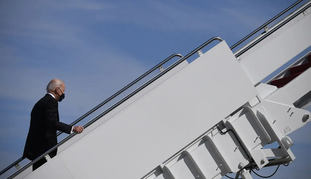 Presiden AS Joe Biden melanjutkan langkahnya setelah tersandung saat menaiki tangga pesawat kepresidenan Air Force One di Pangkalan Udara Andrews, Maryland, Jumat (19/3/2021). Biden yang berusia 78 tahun tidak mengalami cedera dalam kejadian tersebut. (Eric BARADAT/AFP)