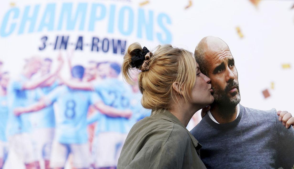 Seorang suporter Manchester City mencium papan bergambar Pep Guardiola saat merayakan gelar juara Liga Inggris di depan Stadion Etihad, Sabtu (20/5/2023). City memastikan gelar juara setelah Arsenal dikalahkan Nottingham Forest dengan skor 0-1 pada lanjutan Liga Inggris 2022/2023 hari Minggu (21/05/2023). (Martin Rickett/PA via AP)