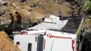 Petugas penyelamat berjalan dekat bus yang jatuh di jalan penghubung Medellin dan Bogota dekat San Luis, Provinsi Antiokia, Kolombia, 27 Desember 2021. Tujuh orang, termasuk seorang wanita hamil, tewas dan 20 lainnya luka-luka ketika sebuah bus terjun ke jurang. (Fredy BUILES/AFP)
