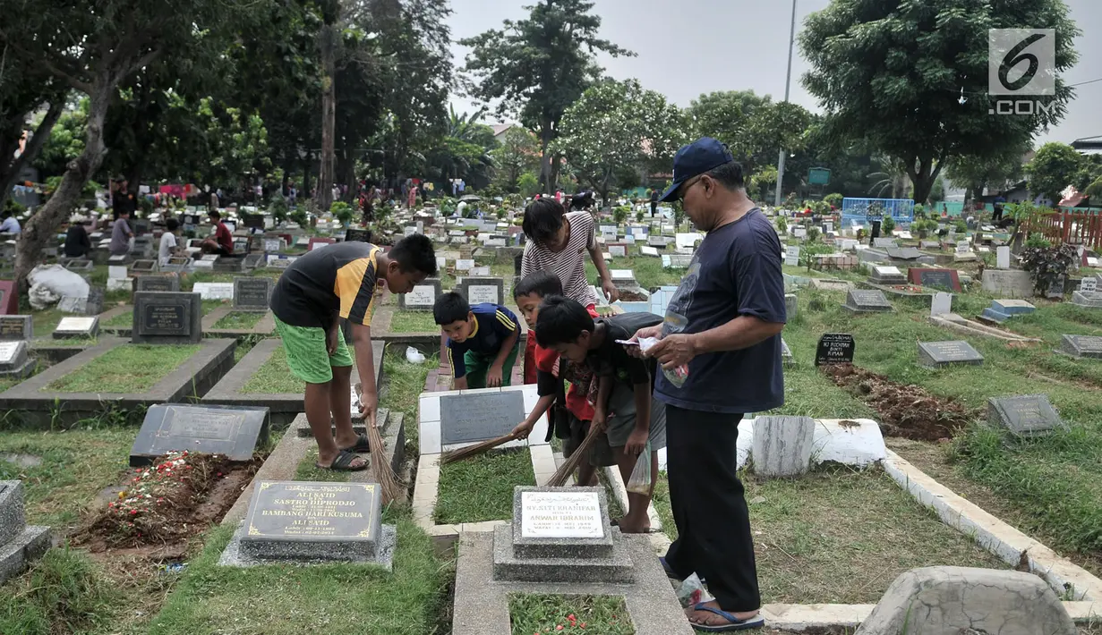 Anak-anak membersihkan makam di TPU Cipinang Baru, Jakarta, Minggu (5/5/2019).  Anak-anak yang mayoritas masih duduk di sekolah dasar ini biasanya melayani jasa Ngoret secara berkelompok dengan tugas masing-masing seperti menyapu dan membersihkan sekitar makam. (merdeka.com/Iqbal S. Nugroho)