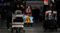 Penumpang mendorong troli barang bawaan saat tiba di Bandara Internasional Beijing pada Senin (20/1/2020). China berada di tengah-tengah kesibukan migrasi manusia tahunan ketika jutaan orang pulang ke kampung halaman mereka untuk menikmati libur Tahun Baru Imlek bersama keluarga. (WANG Zhao/AFP)