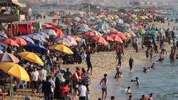 Pengunjung memadati pantai Beit Lahia di Jalur Gaza utara saat para siswa memulai liburan musim panas mereka pada 3 Juni 2022. Sejumlah warga Palestina menikmati musim panas dengan berenang dan bermain air di pantai. (MOHAMMED ABED / AFP)