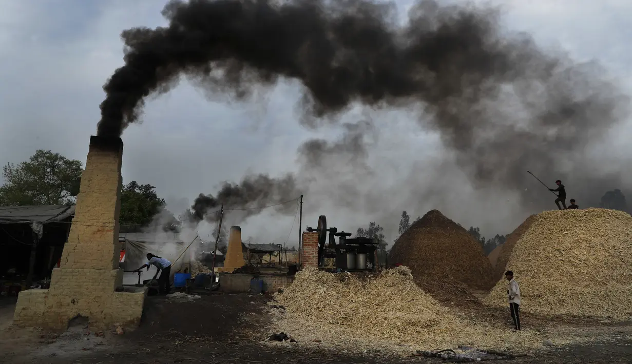 Asap mengepul dari cerobong asap saat pekerja menyiapkan gula merah di pinggiran Bareilly, India, Selasa (23/3/2021).  Jaggery adalah gula tradisional yang tidak dimurnikan yang dikonsumsi di banyak bagian Asia, terbuat dari molase tebu dan nira kurma. (AP Photo/Rajesh Kumar Singh)