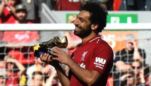 Penyerang Liverpool, Mohamed Salah, mengankat trofi Sepatu Emas Premier League usai laga melawan Brighton & Hove Albion di Stadion Anfield, Minggu (13/5/2018). Salah menjadi top scorer Premier League musim ini dengan raihan 32 gol. (AFP/Paul Ellis)