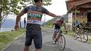 Seorang asisten tim memberikan minum kepada pebalap yang melintas jalur kelok 44  etape ke-4 Tour de Singkarak 2016 di Kabupaten Agam, Sumatera Barart. (Bola.com/NIcklas anoatubun)