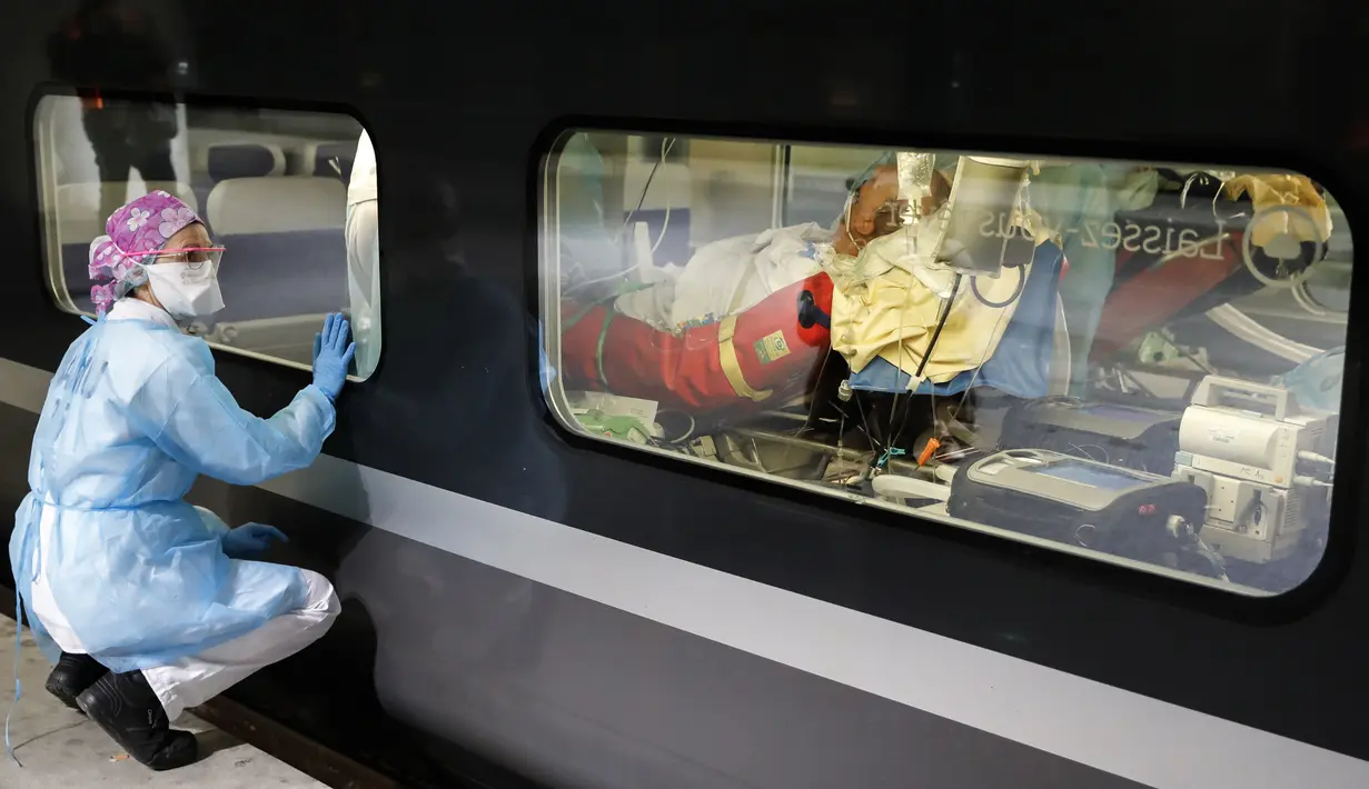 Petugas medis melihat pasien virus corona COVID-19 dalam kereta kecepatan tinggi TGV dari peron Stasiun Gare d'Austerlitz di Paris, Prancis, Rabu (1/4/2020). Prancis mengerahkan kereta kecepatan tinggi untuk mengevakuasi pasien COVID-19 dari Paris ke wilayah Brittany. (Thomas SAMSON/AFP/POOL)