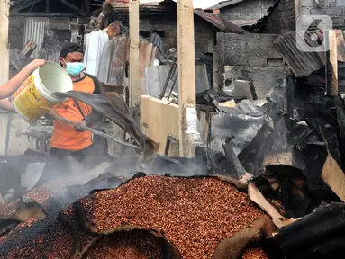 Pedagang menyiram air pada sisa bara api lokasi kebakaran Pasar Ciputat, Tangerang Selatan, Banten, Kamis (12/5/20222). Kebakaran Pasar Ciputat pada kemarin sore menghanguslan lebih dari 50 kios dan rumah warga yang berada di sekitar pasar. (merdeka.com/Arie Basuki)