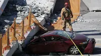 Sebuah mobil hancur akibat tertimpa jembatan pejalan kaki yang runtuh di Miami, Florida (15/3). Jembatan ini menghubungkan Universitas Internasional Florida dengan kos atau asrama mahasiswa. (Joe Raedle/Getty Images/AFP)