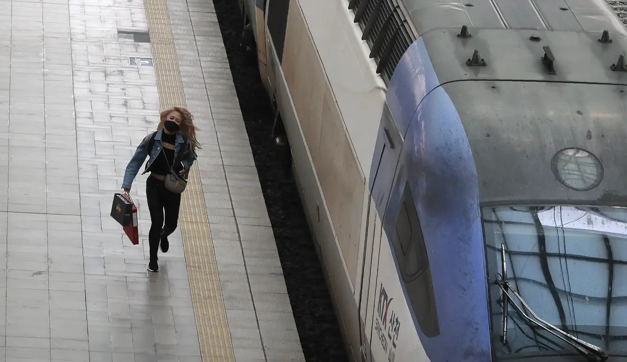 Seorang wanita yang mengenakan masker untuk membantu melindungi dari penyebaran virus corona berlari ke kereta menjelang liburan Chuseok atau Hari Thanksgiving versi Korea di Stasiun Kereta Seoul di Seoul, Korea Selatan, Selasa (29/9/2020). (AP Photo / Ahn Young-joon)