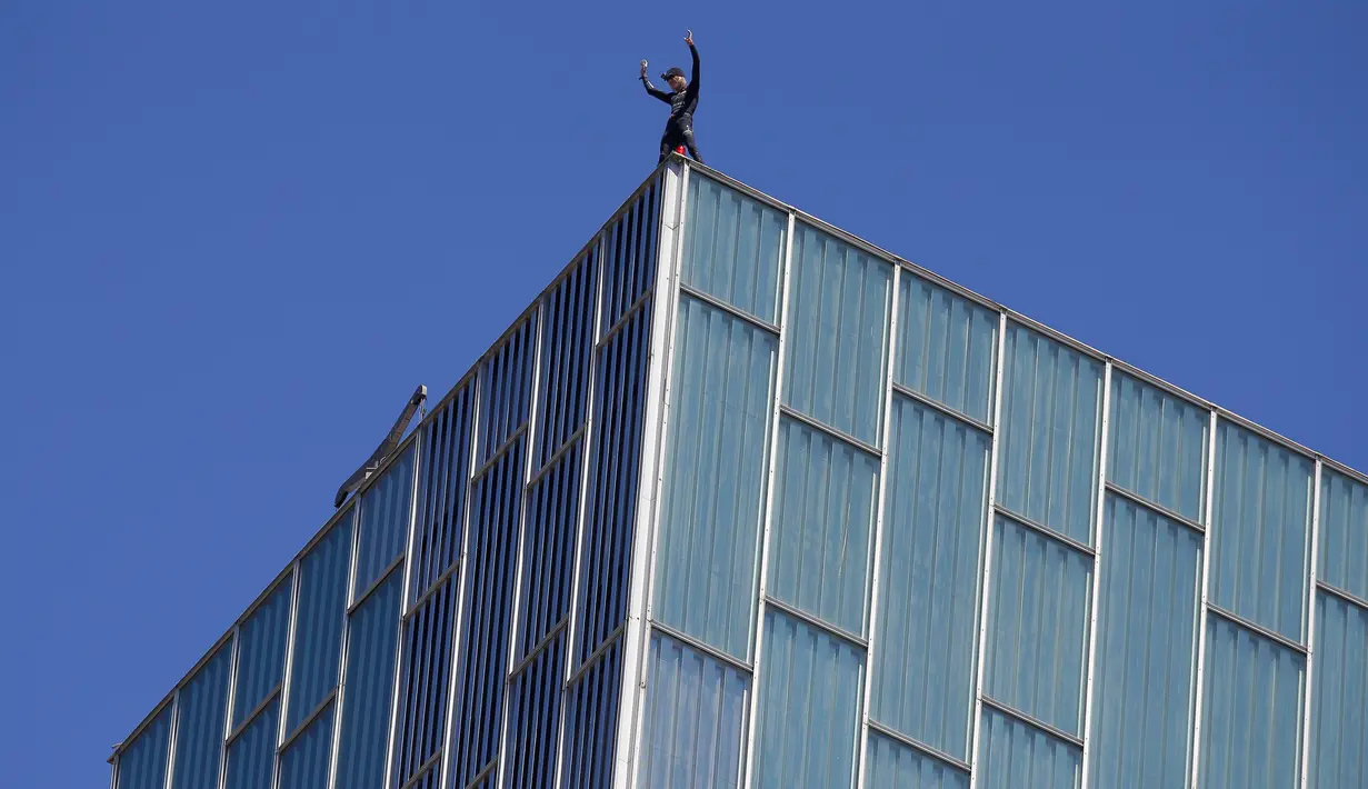 Pemanjat asal Prancis Alain Robert, melambaikan tangan setelah berhasil memanjat Melia Barcelona Sky Hotel di Spanyol, Senin (12/6). Pria 55 tahun itu butuh waktu 20 menit untuk memanjat gedung setinggi 116 meter tanpa pengaman. (AP Photo/Manu Fernandez)