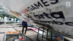 Pekerja memeriksa papan sosialisasi Asian Games 2018 yang roboh akibat hujan angin di Bundaran HI, Jakarta, Senin (11/9). Kontruksi besi penahan baliho patah Akibat hujan angin yang mengguyur Jakarta minggu (10/9) malam. (Liputan6.com/Faizal Fanani)